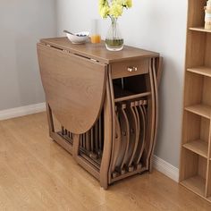 a wooden table with some flowers in a vase on top of it and shelves next to it