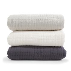 three blankets stacked on top of each other in white and grey colors, with one blanket folded