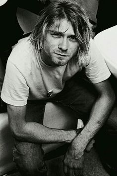 black and white photograph of a man with long hair sitting on the floor in front of other people