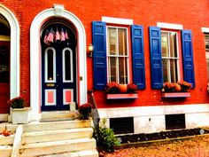 a red brick building with blue shutters on the front door and steps leading up to it