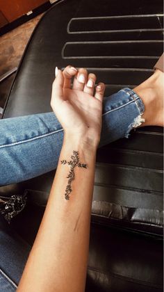 two hands holding each other with a cross tattoo on their wrist and the other arm