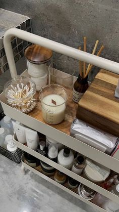 a shelf filled with lots of different types of beauty products and candles on top of it