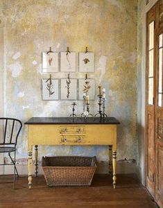 an old table with pictures on the wall above it and a chair in front of it