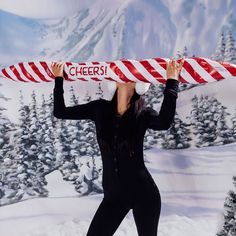 a woman in a black bodysuit holding a candy cane over her head with the words cheers on it