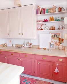 a kitchen with pink cabinets and pictures on the counter top, along with other items