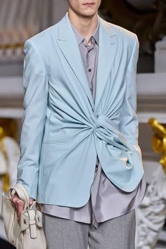 a man in a light blue suit and tie on the catwalk at a fashion show