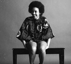 a black and white photo of a woman sitting on a bench with her legs crossed