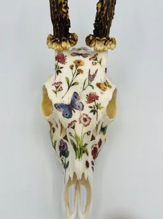 an animal skull with two birds on it's head and flowers painted on the front