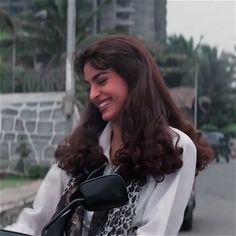 a woman with long hair is smiling while riding a motorcycle