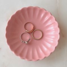 two wedding rings are sitting on a pink plate