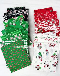 four different colored christmas wrappings laid out on a white tablecloth with snowflakes, candy canes and santa hats