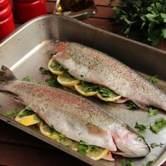 two fish in a pan with lemon slices and parsley