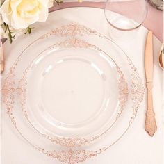 a table setting with white and gold plates, silverware and flowers on the table