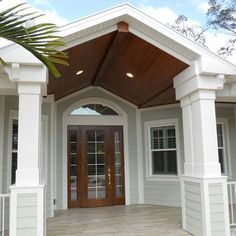 the front entrance to a house with white trim and wood accents