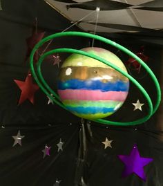 a colorful ball hanging from the ceiling with stars around it and an object in the middle