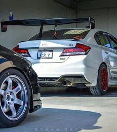 two cars parked side by side in a garage with their hoods open and the back end