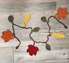 crocheted leaves and acorns are arranged on a wood floor