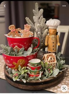 three red mugs filled with cookies on top of a wooden tray next to succulents