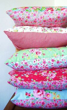 a stack of four pillows sitting on top of a wooden table next to a wall