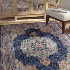 a blue rug with an ornate design on the bottom and sides, in front of a wooden cabinet