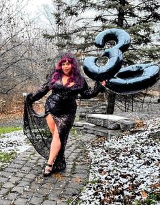 a woman with purple hair is holding an inflatable number