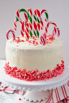 a cake with white frosting and red sprinkles topped with candy canes