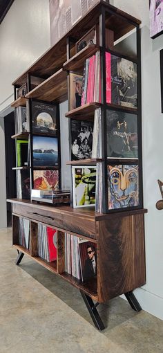 a wooden shelf filled with vinyl records and cd's on top of metal legs