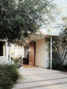 an entrance to a house with trees in the front and side doors on both sides