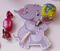 an elephant holding a candy lollipop on top of a table next to other candies