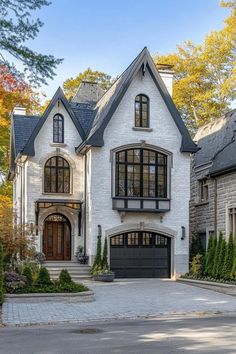 a large white brick house with black trim and arched windows on the front, surrounded by trees