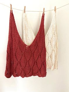 two crocheted tops hanging on a clothes line, one in red and the other in white