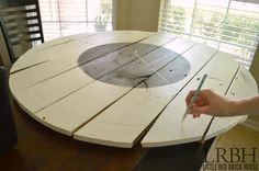 a person holding a pen in front of a wooden table with a clock on it