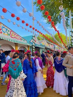 many people are dressed up and walking around in colorful dresses at an outdoor fair or festival