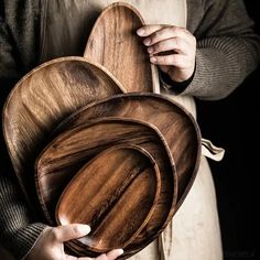 a person holding three wooden plates in their hands