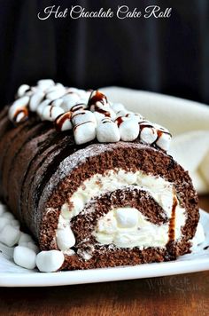 a chocolate cake roll with marshmallows on top is sitting on a plate