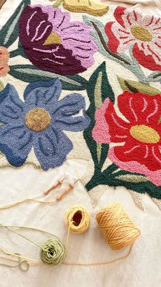 yarn and crochet are laid out on a tablecloth with flowers in the background