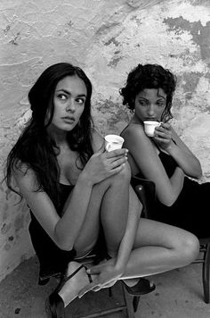 two women sitting on chairs holding coffee cups