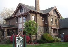 a stone and brick house with a sign in front of it that says stone is the foundation for this house