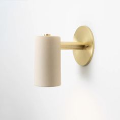 a wall light with a white shade on it's side and a gold arm