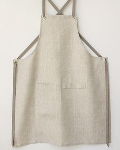 an apron hanging on the wall with a wooden hanger over it's shoulder