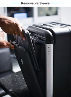 a person holding onto a black and silver piece of luggage