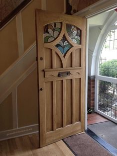 an open wooden door sitting inside of a room next to a stair case with stained glass panels