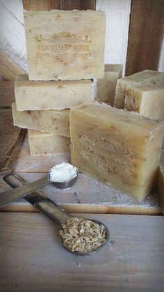 several bars of soap sitting on top of a wooden table next to a scoop of oatmeal