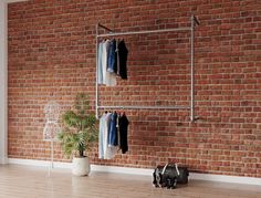 a brick wall with clothes hanging on it and a potted plant in the foreground