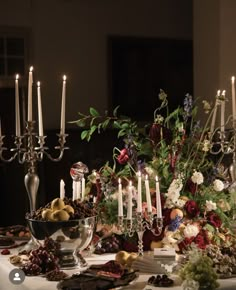 a table is set with candles, flowers and fruit for a festive dinner party