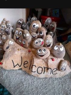 some rocks with faces painted on them and the words welcome are in front of it