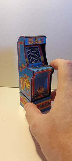 a hand is holding an old fashioned video game in it's left side view