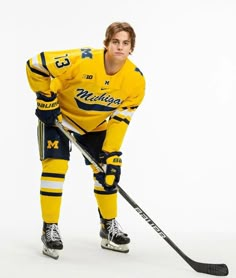 a male ice hockey player in a yellow jersey and black pants posing for the camera