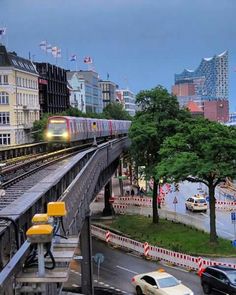 a train traveling down tracks next to tall buildings and traffic lights on a city street