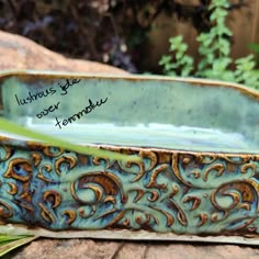 a blue and green planter sitting on top of a stone slab next to plants